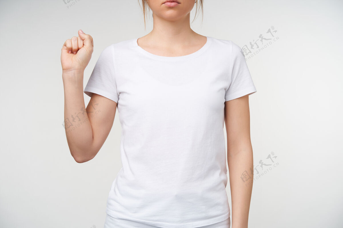 非语言摄影棚拍摄的年轻女性裸体修指甲握紧拳头 同时展示手语上的字母s 穿着白色t恤在白色背景下被隔离皮肤白皙成人翻译