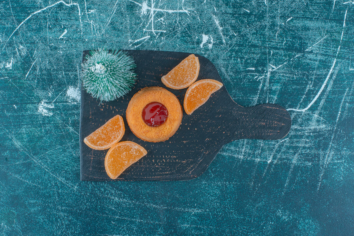 甜食果冻填充蛋糕 marmelades和一个树雕像在蓝色背景的黑色板上高质量的照片烘焙果冻果酱