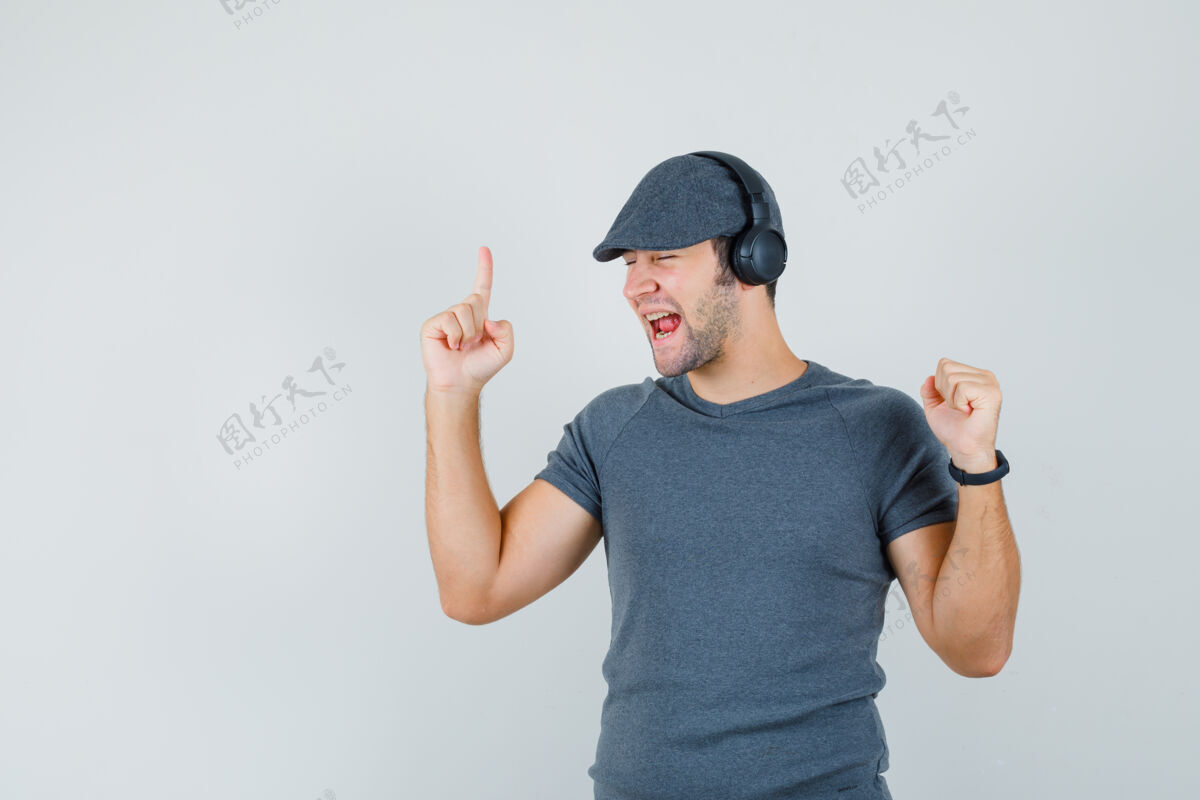 享受穿着t恤 戴着帽子 戴着耳机欣赏音乐的年轻男性 看上去很活泼 前视图孩子远景帽子