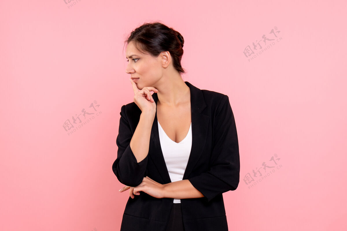 年轻女性正面图穿着深色夹克的年轻女性在粉色背景上思考粉色思考夹克