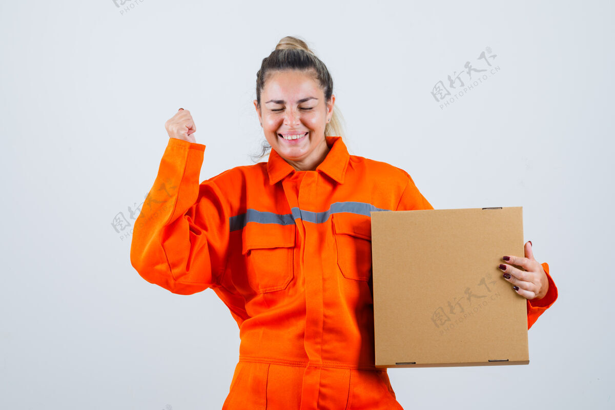 盒子年轻女性展示获奖者的姿态 同时手持工人制服的盒子 看上去很愉快前视图人举行工人