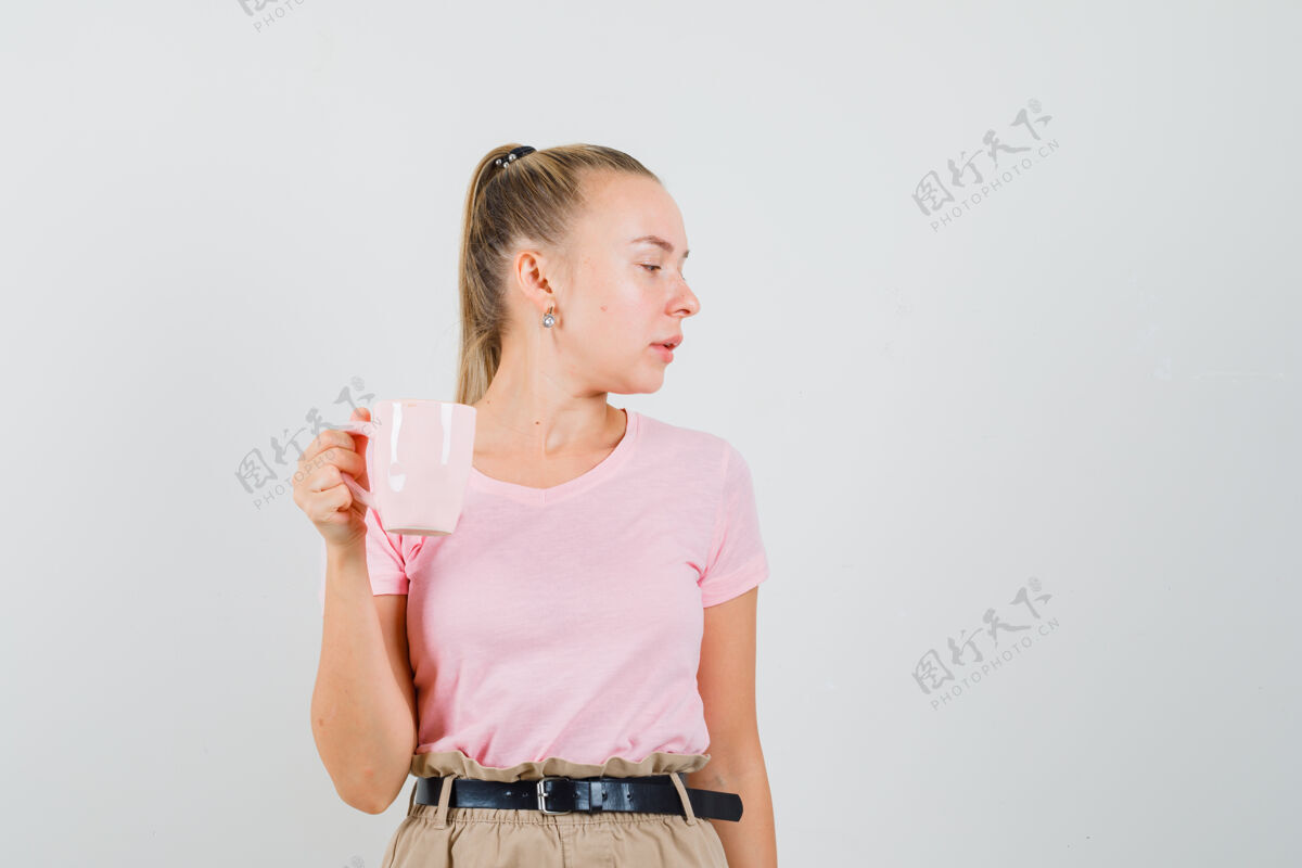 肖像金发女孩穿着t恤 裤子里拿着一杯饮料 往旁边看 前面看手旁白茶
