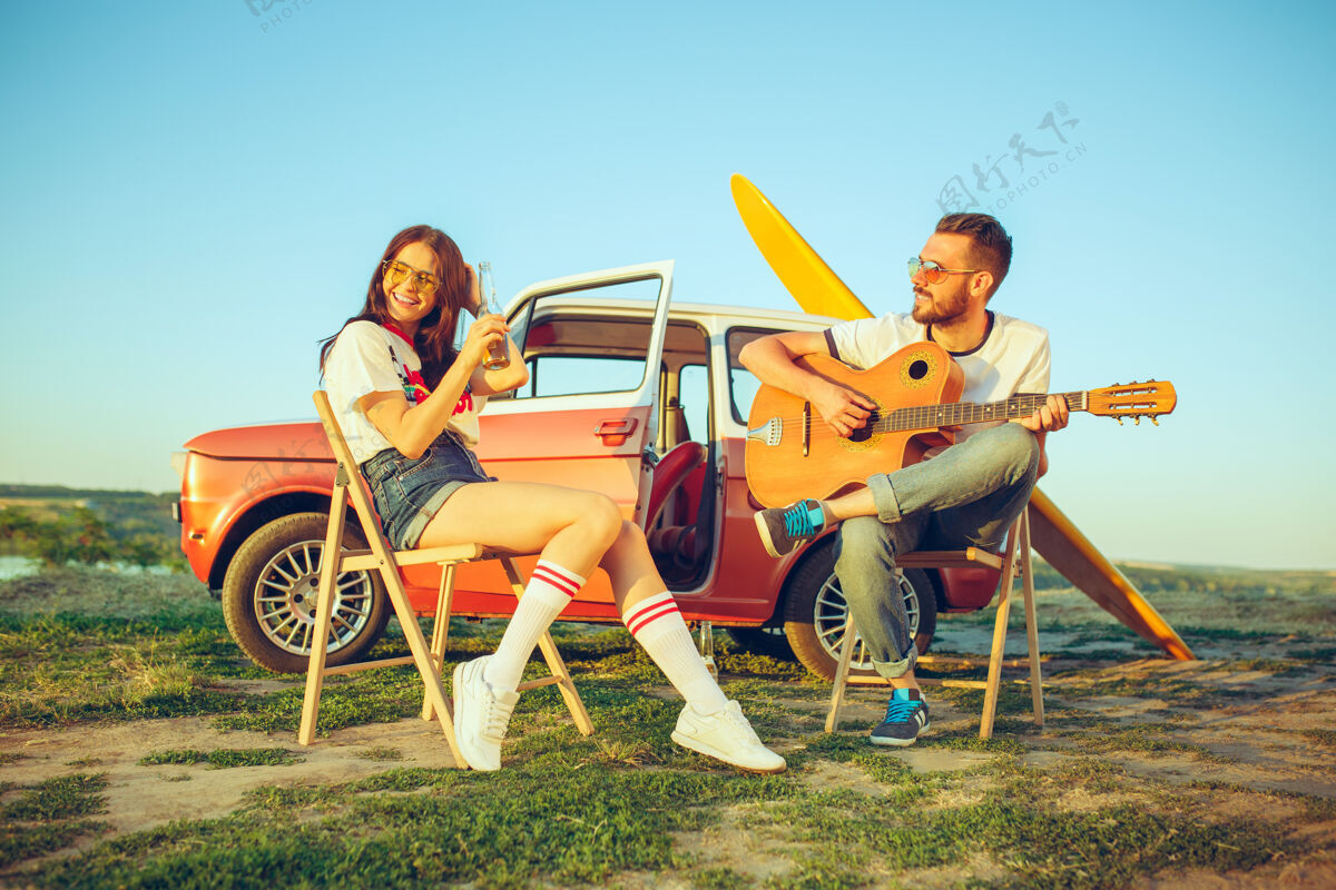 年轻一对情侣坐在沙滩上休息 在河边的夏日里弹吉他自然一起情侣