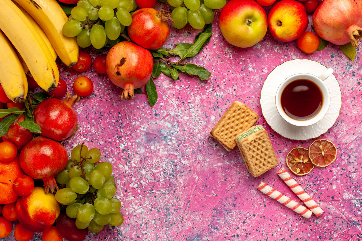 顶级顶视图新鲜水果组成五颜六色的水果与茶和华夫饼在粉红色的表面苹果饮食五颜六色