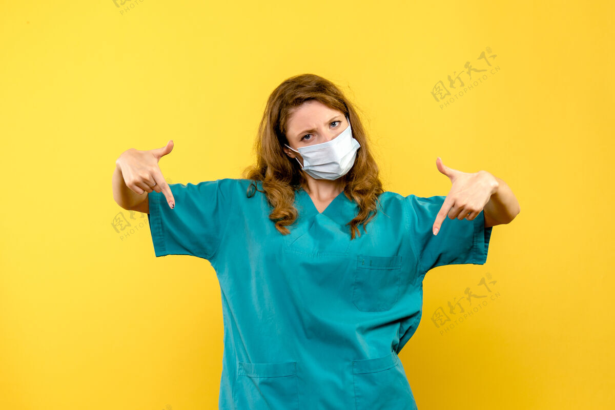 面具黄色空间里戴着面具的年轻女医生的正面图流行年轻女医生生活方式