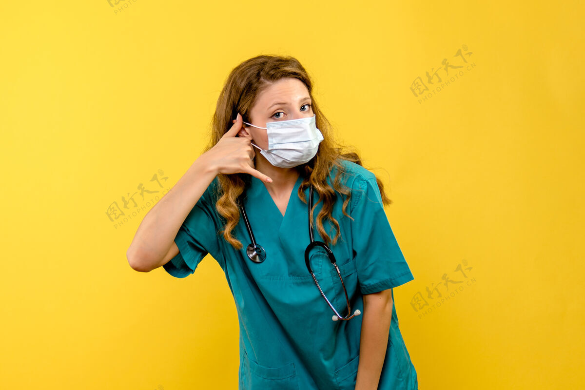 健康黄色空间里戴着面具的女医生的正视图人电话人