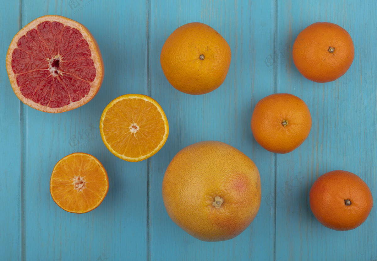 绿松石色在绿松石色背景上 可以看到切片和整个橘子和葡萄柚的顶视图切片葡萄柚水果