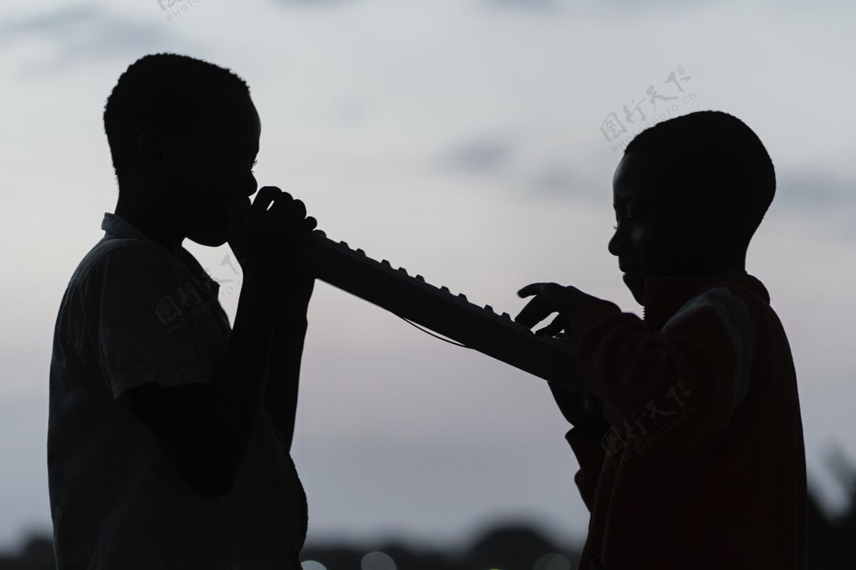 孩子两个非洲孩子在夕阳下演奏乐器肖像日落男孩