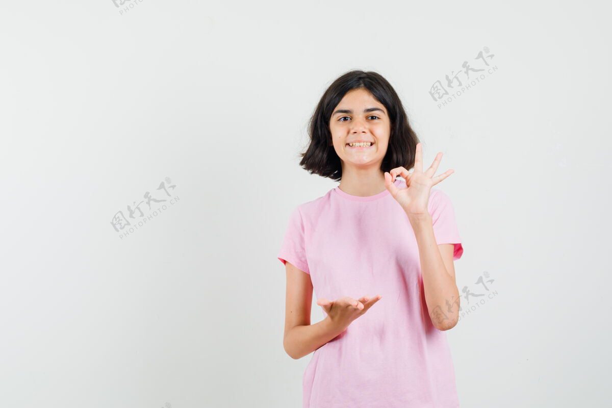 确定穿着粉色t恤的小女孩显示ok标志 掌心张开 看起来很开心 正面视图女孩年轻保持