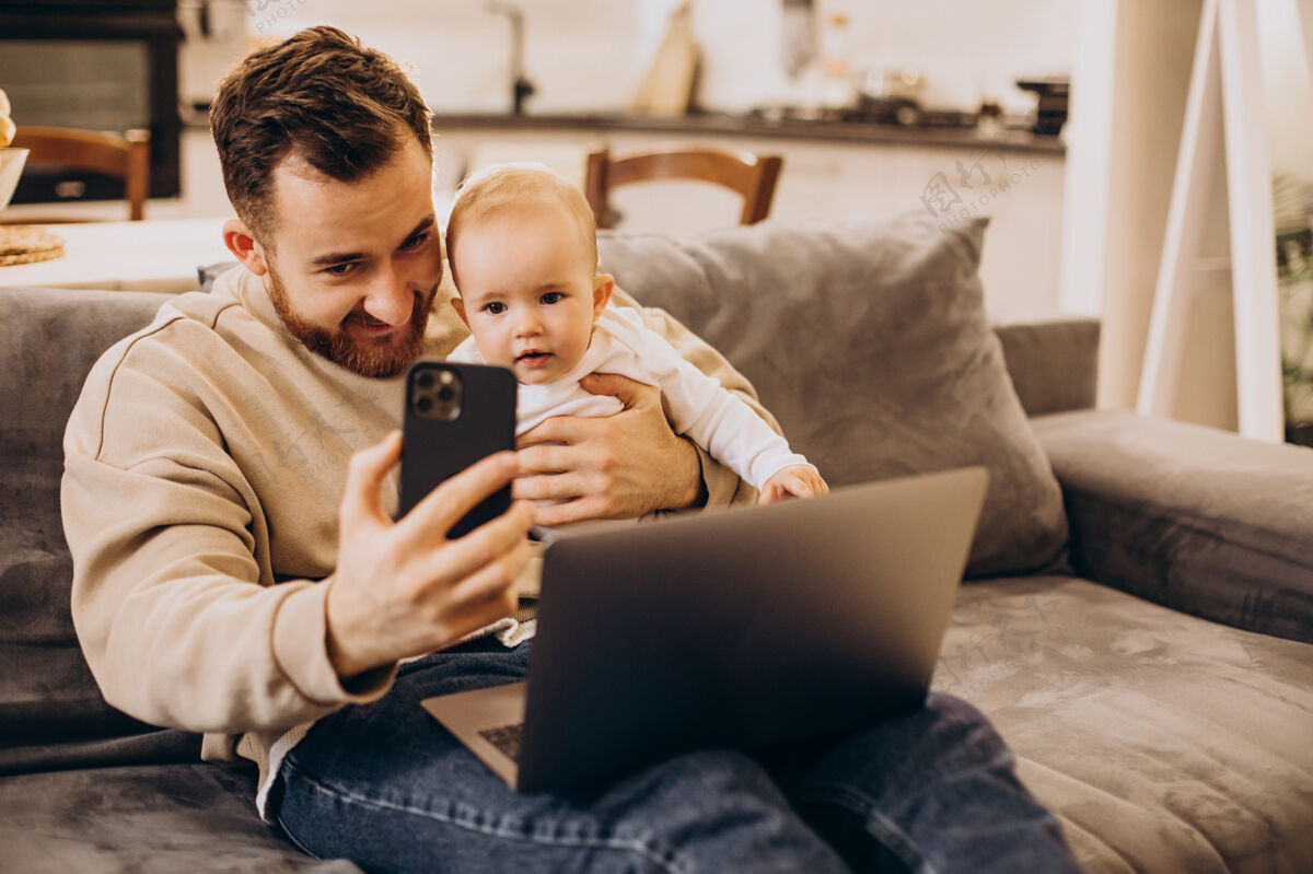爸爸年轻的父亲和他的女婴坐在一起 在家里用电脑设备快乐的男人电影
