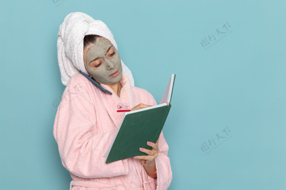 自理正面图身着粉色浴袍的年轻女性淋浴后在蓝色墙上讲电话美容水自理淋浴干净电脑个人电脑个人