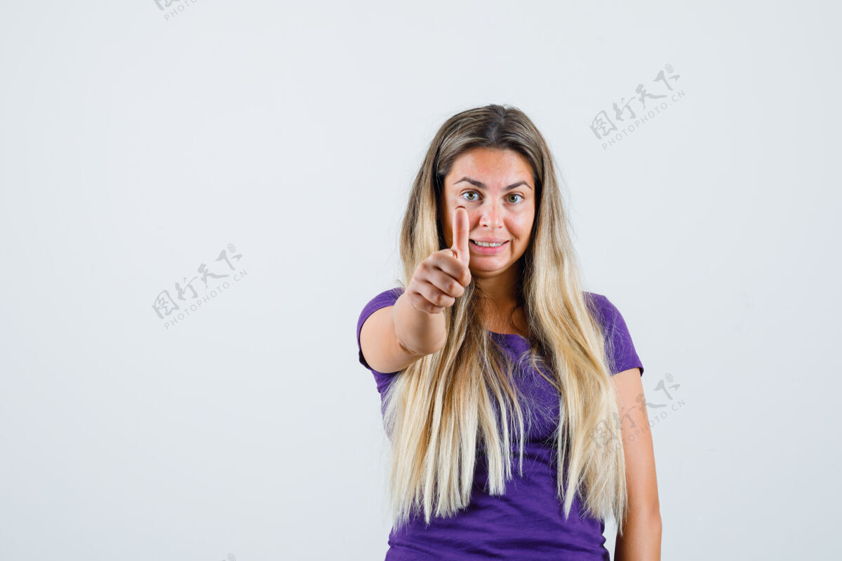时尚身着紫罗兰色t恤的金发女士向上竖起大拇指 看起来很快乐 正面视图优雅漂亮人