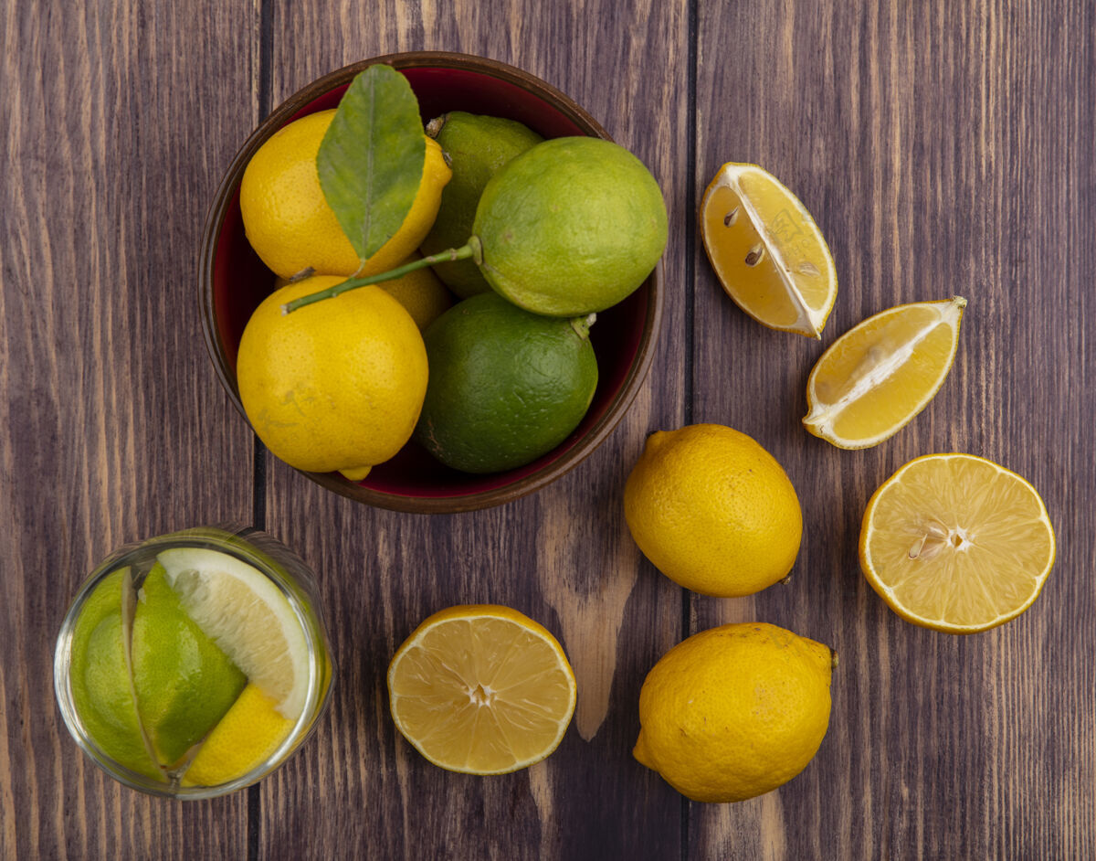 柑橘顶视图柠檬与柠檬在碗和一杯排毒水的木材背景酸橙柠檬碗