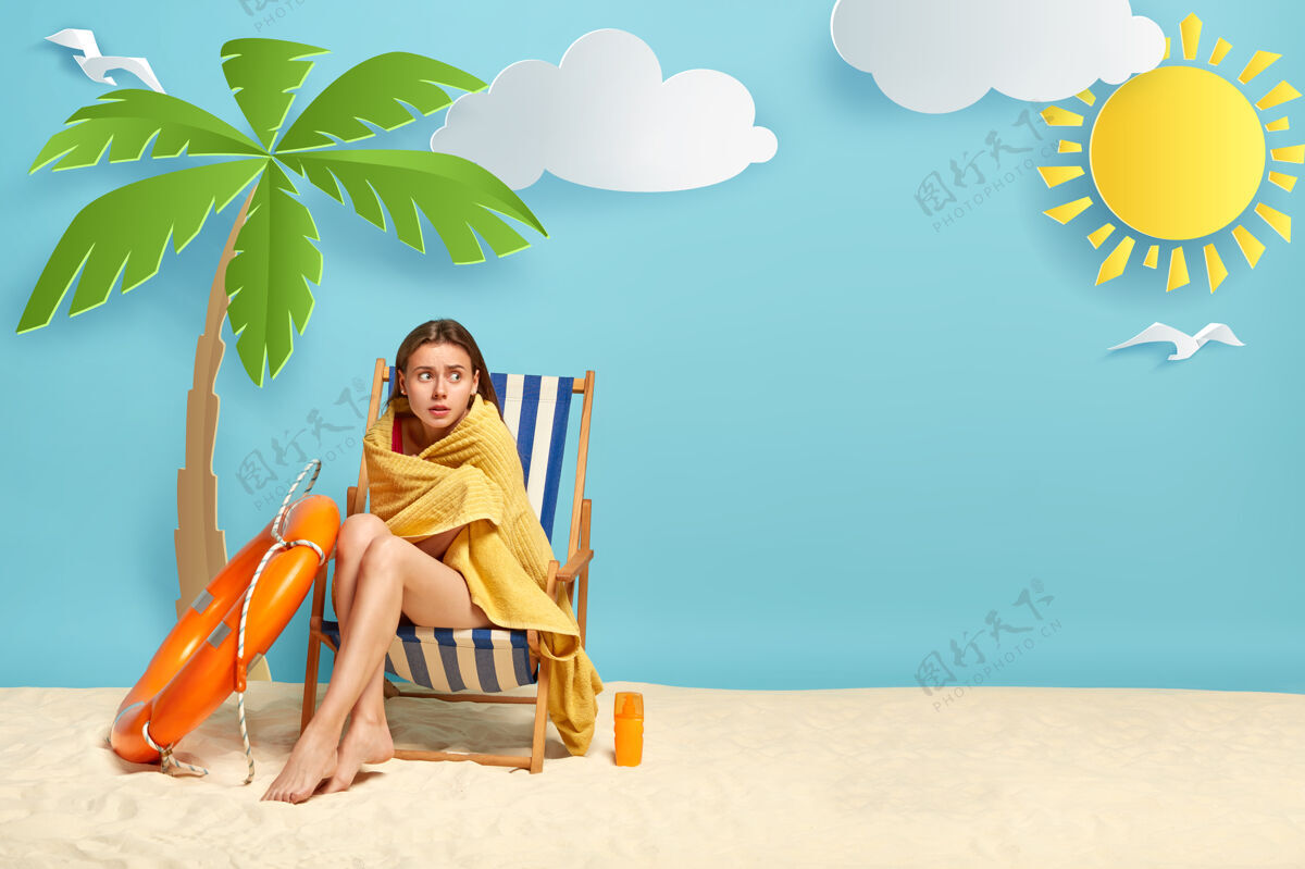 沙滩可爱的女人在海里游泳后觉得冷 就坐在棕榈树旁的躺椅上椅子旁边棕榈树