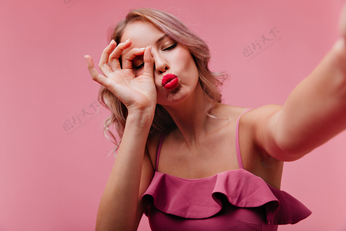 时尚浪漫的红唇女人在室内拍照时摆出亲吻的表情魅力现代女孩