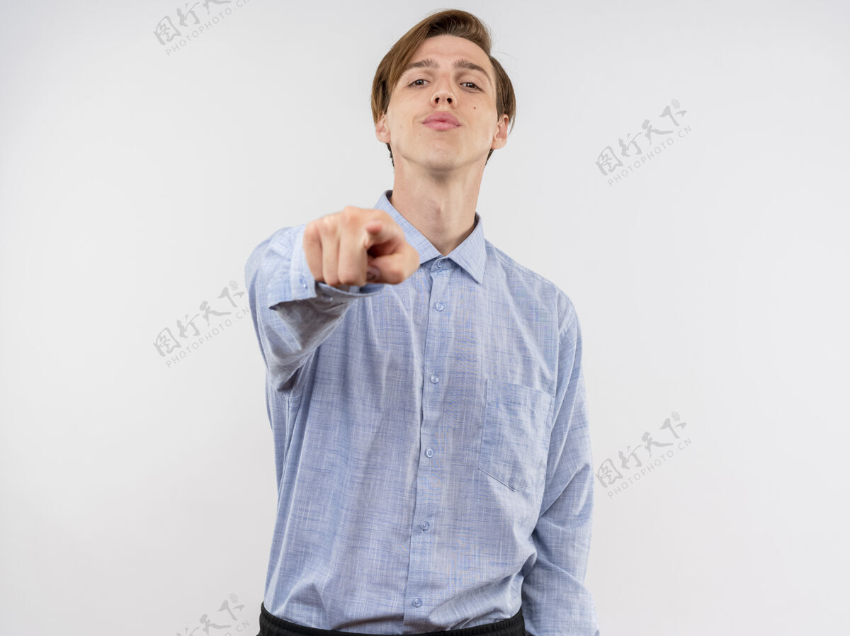 年轻穿蓝色衬衫的年轻人用食指指着白色的墙壁微笑着自信 快乐和积极手指积极目录