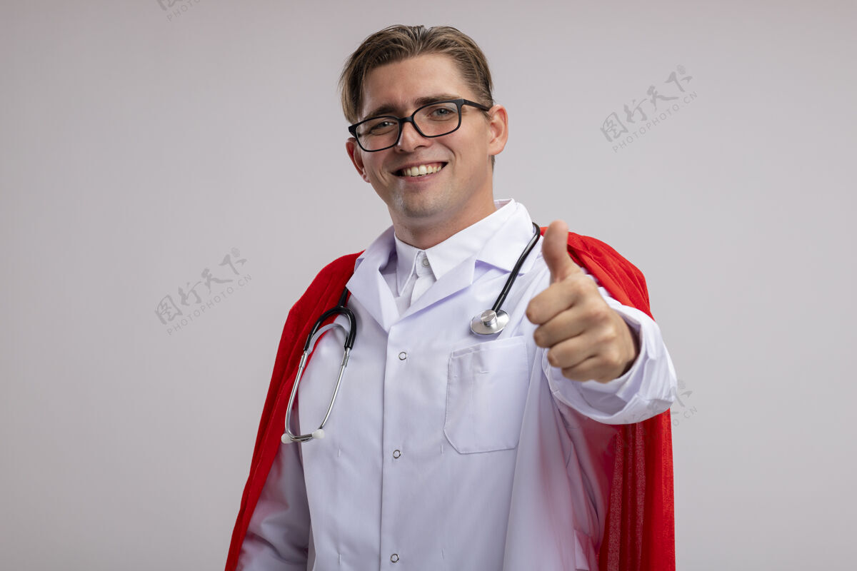超级超级英雄医生 身穿白大褂 披着红斗篷 戴着眼镜 脖子上戴着听诊器 脸上带着微笑 站在白墙上竖起大拇指秀听诊器脖子