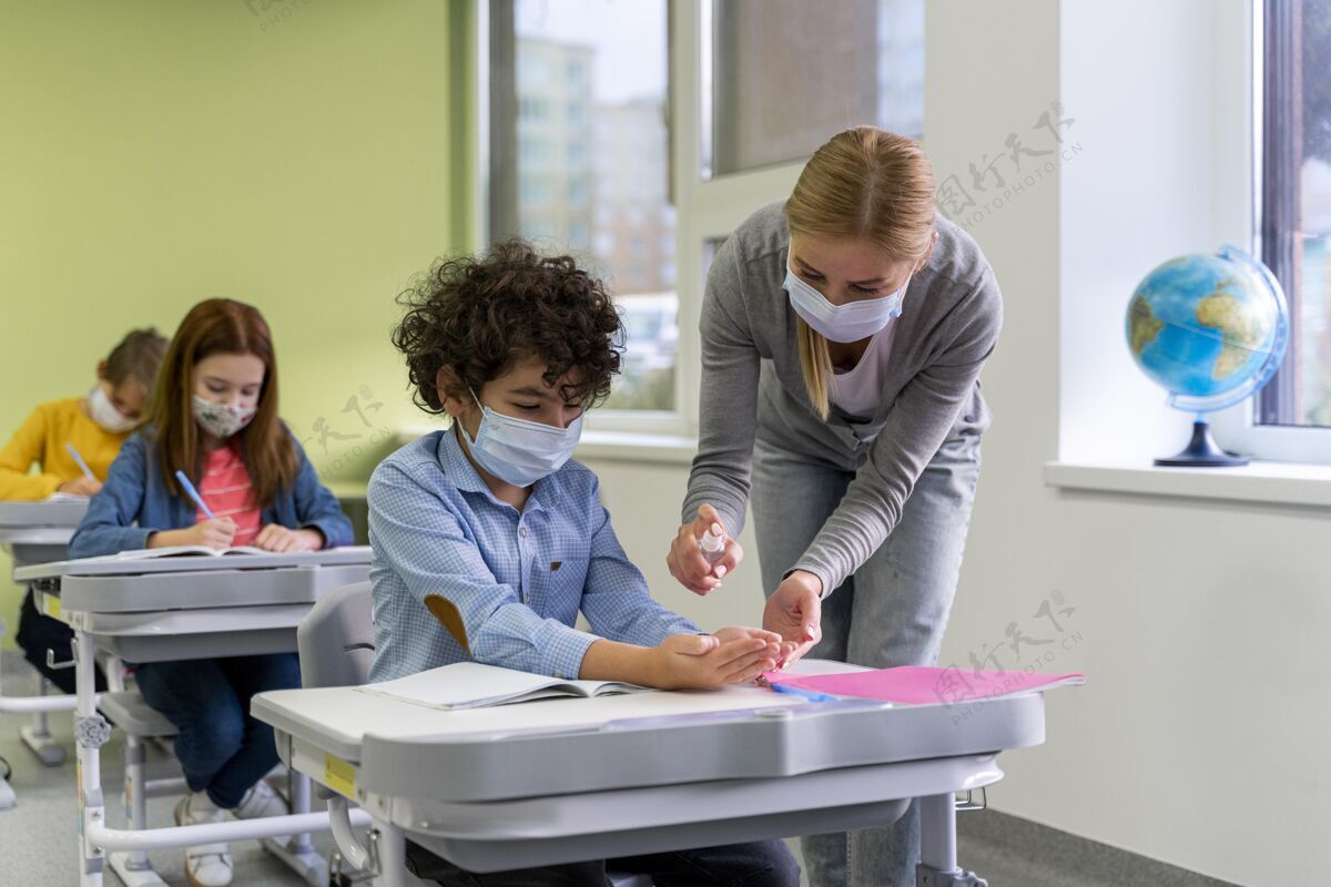孩子带着医用口罩的女老师在教室里给孩子们洗手新常态学校课堂