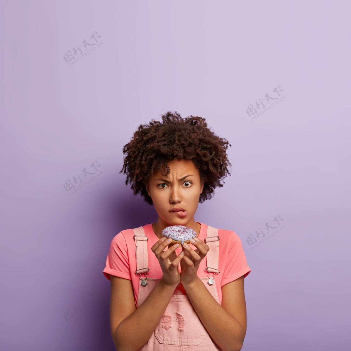 人类年轻的不高兴的女人拿着美味的甜甜圈服装糖吃