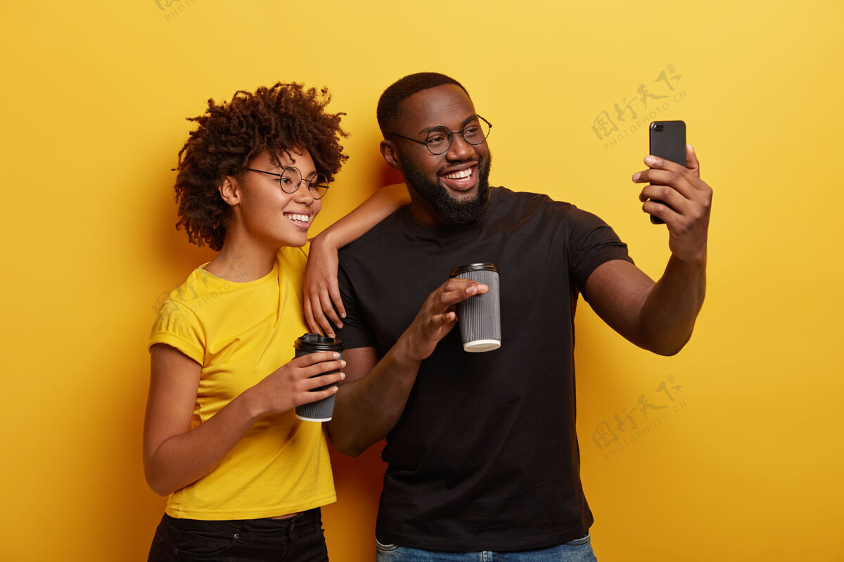 喜悦幸福的黑皮肤情侣在咖啡休息时间尽情享受 在现代手机上自拍 戴上圆眼镜饮料兴奋手机
