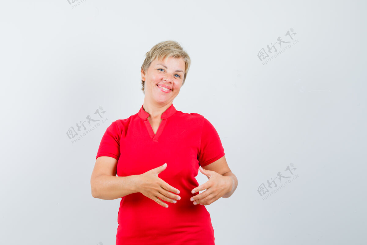 肖像穿红色t恤的成熟女人假装拿着什么东西 看起来很快乐人快乐姿势