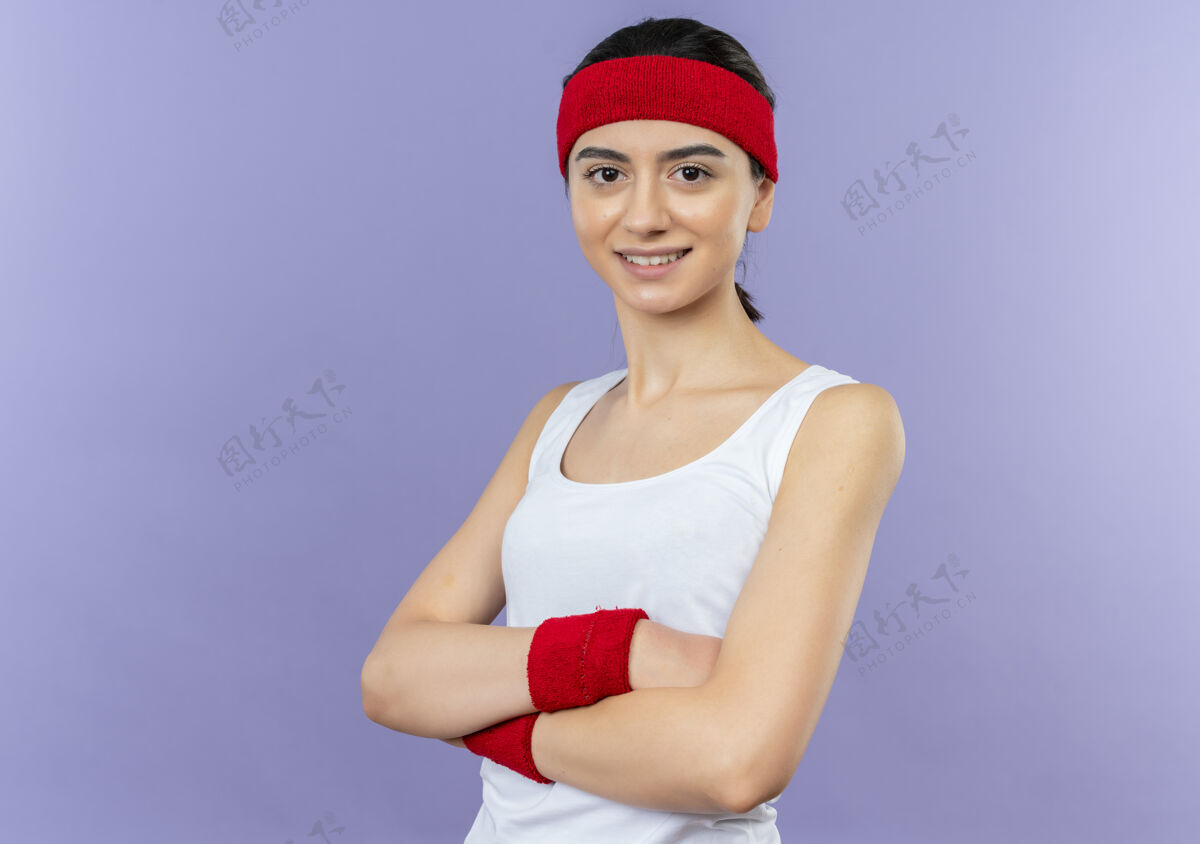 公民身穿运动服 头箍 双臂交叉 自信地站在紫色墙壁上的年轻健身女士微笑手臂自信