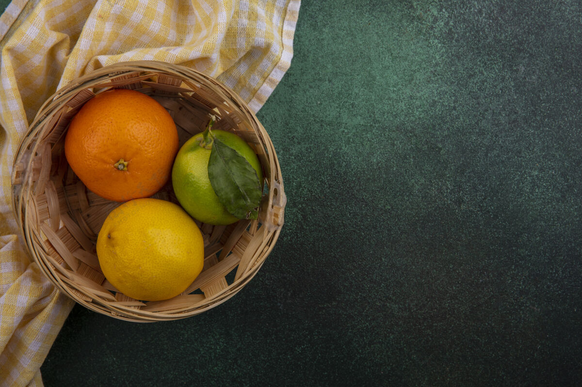 格子顶视图复制空间橙色与柠檬和柠檬在篮子与黄色格子毛巾绿色背景绿色柠檬色黄色