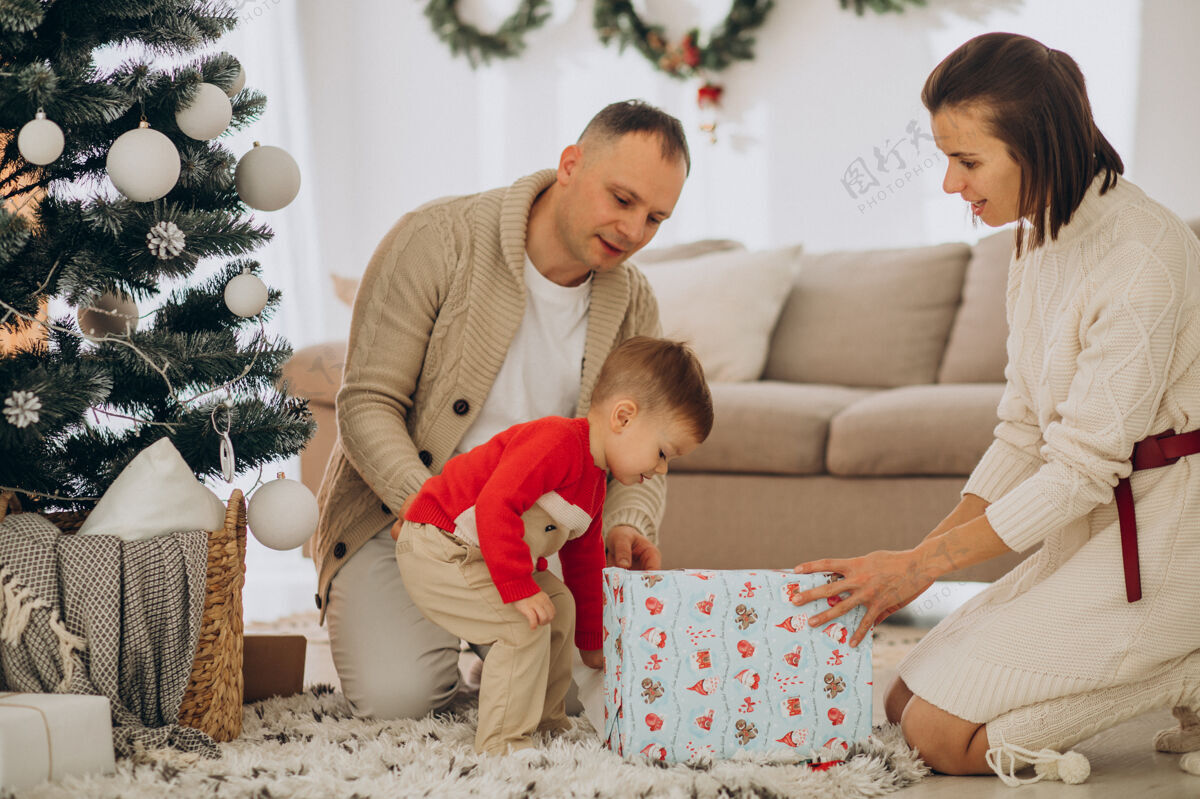 装饰一家人带着小儿子在家里的圣诞树旁过圣诞节现代父母儿子