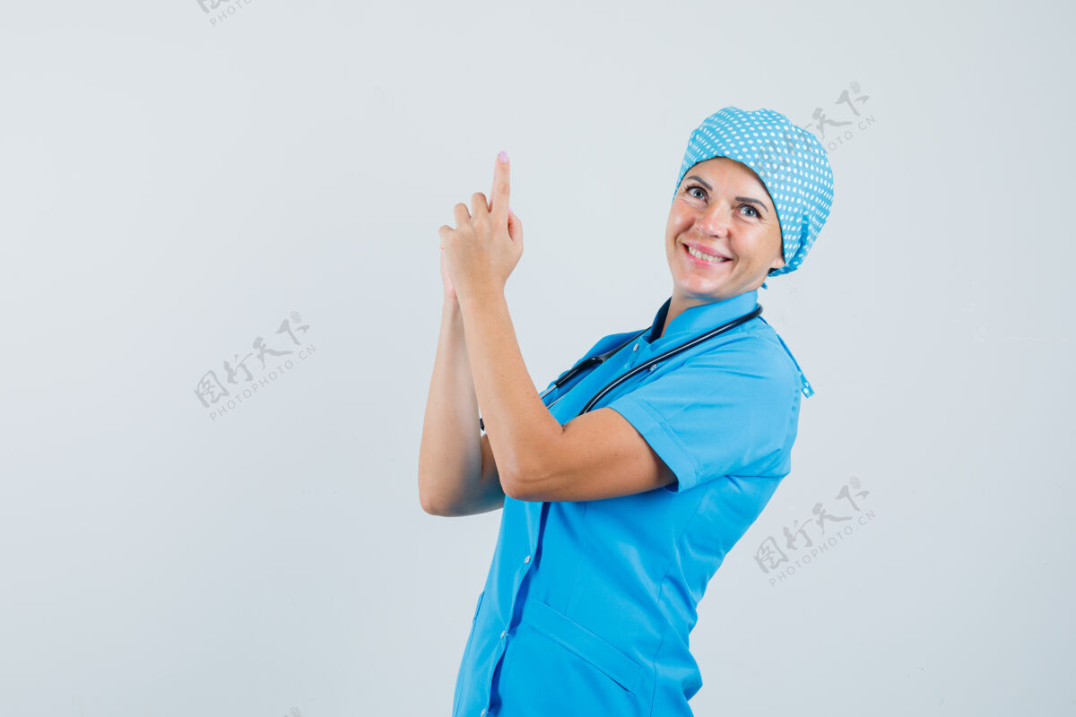 治疗身着蓝色制服的女医生正在做手指手枪的招牌 看上去很欢快 正前方视图诊所预防职员