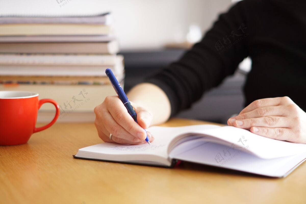 通讯一个在家工作或学习的妇女的特写镜头 旁边有一个红色的咖啡杯现代无线家庭作业