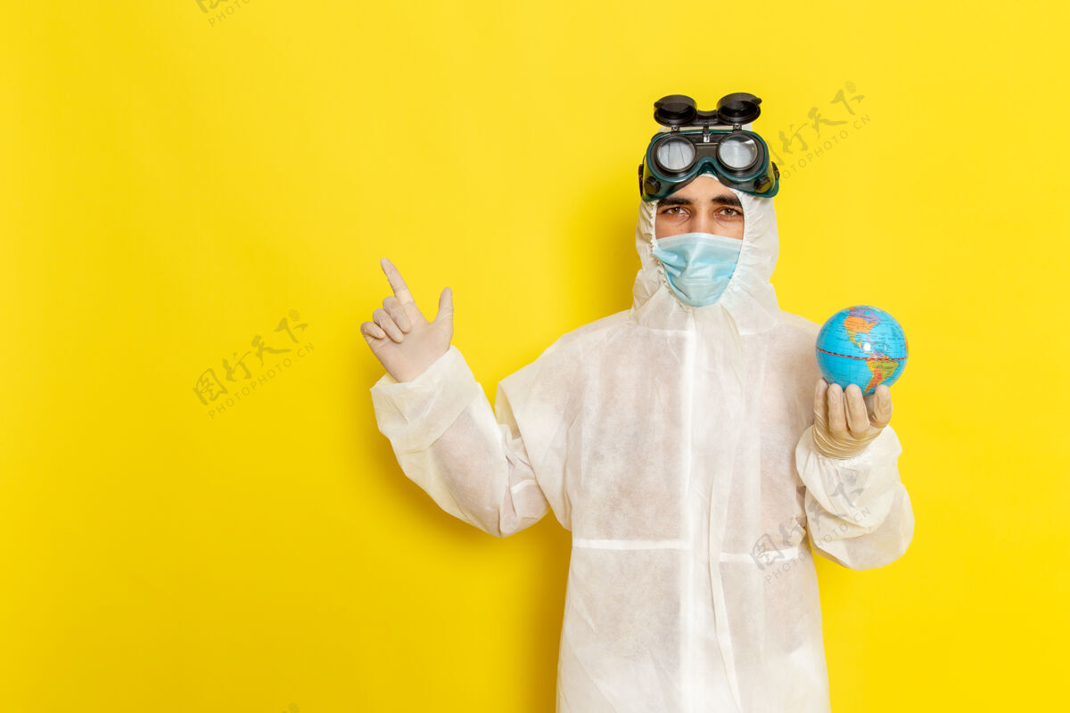 手持正面图：黄色办公桌上 一位身着特殊套装的男科学工作者手持小圆球正面圆工人