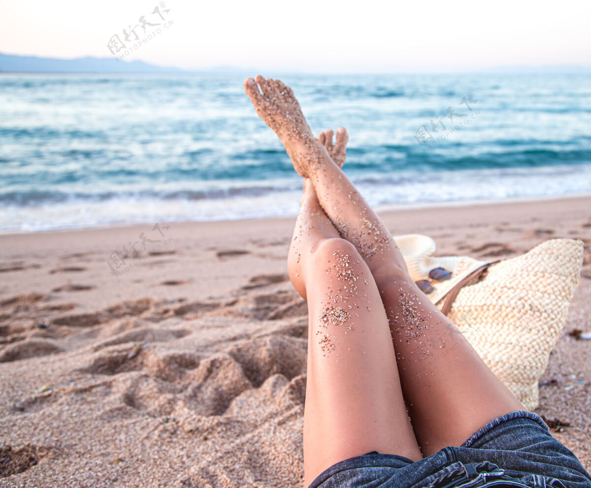 休息身体的一部分女性的脚在沙滩上靠近海边的沙滩上女孩美腿减肥
