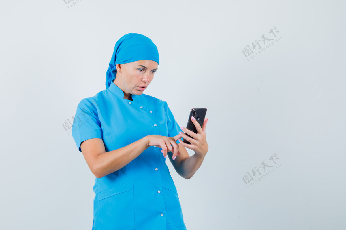 制服穿着蓝色制服的女医生正在用手机 看上去很惊讶治疗手机诊所