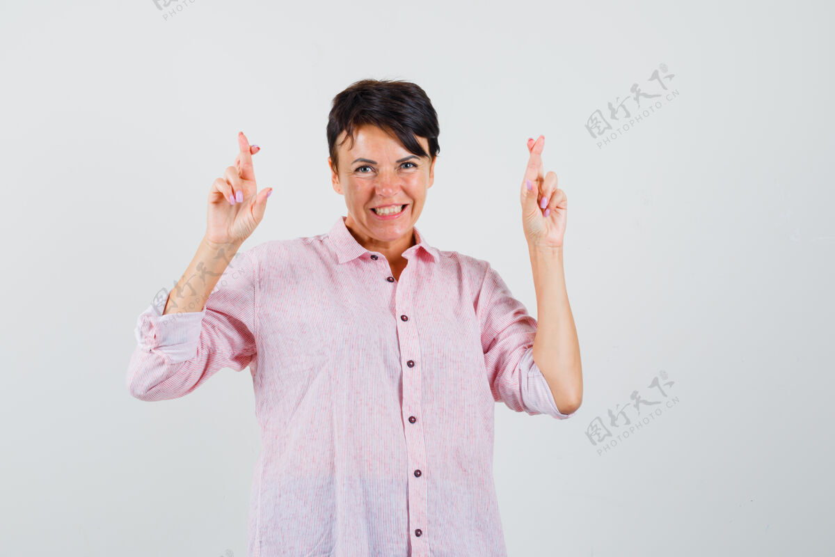 爆发女性穿着粉色衬衫 手指交叉 看起来很高兴正面视图保护疾病成人