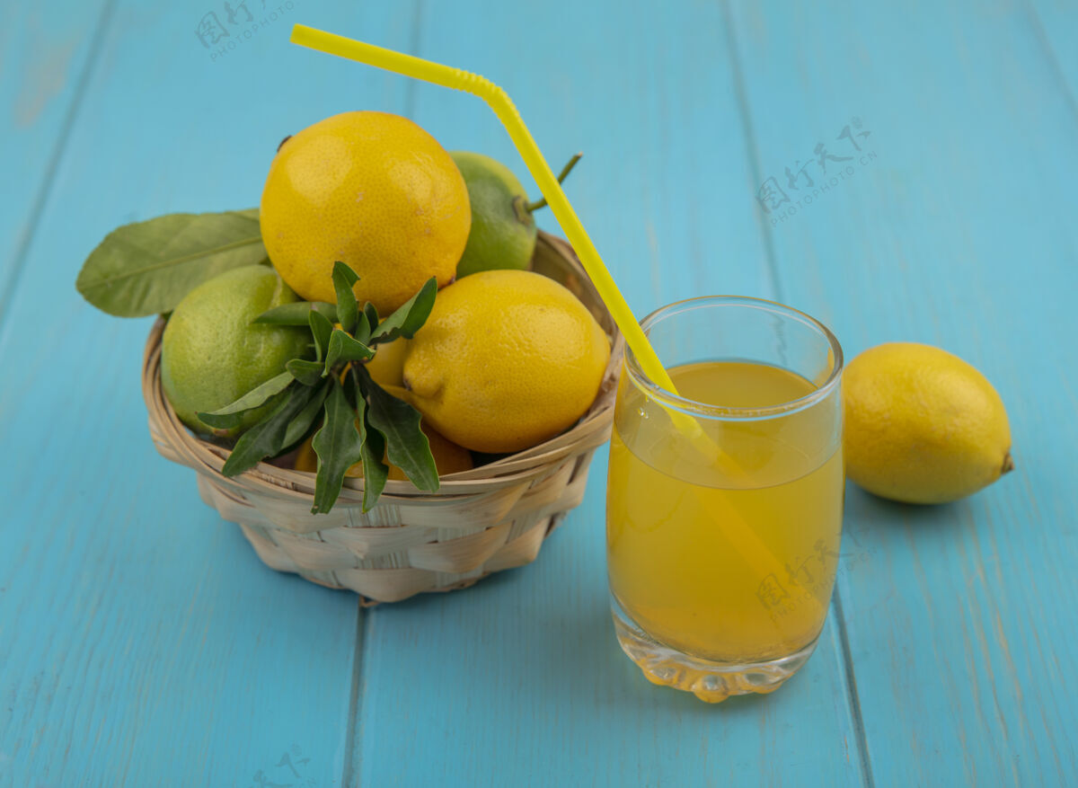 风景侧视图：篮子里的柠檬和酸橙 绿松石背景上的柠檬汁水果玻璃杯柠檬