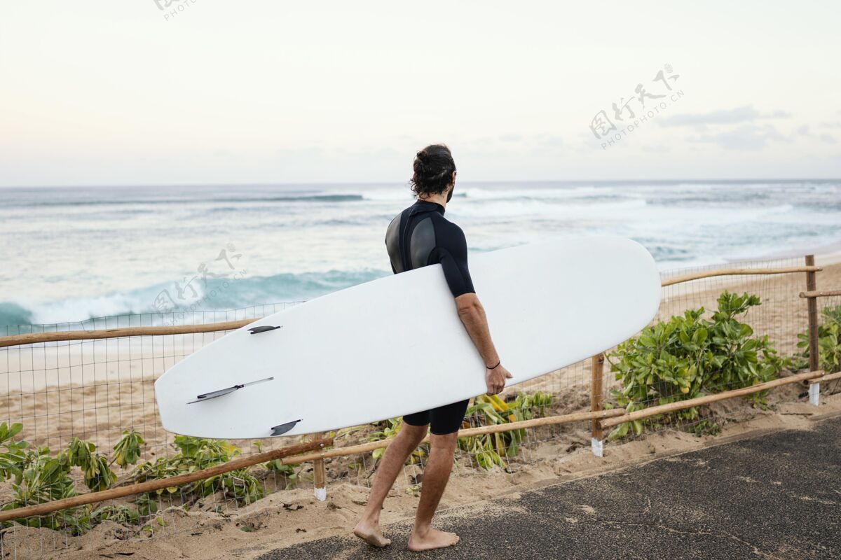 夏威夷一个穿着冲浪服拿着冲浪板的男人生活方式夏季冲浪