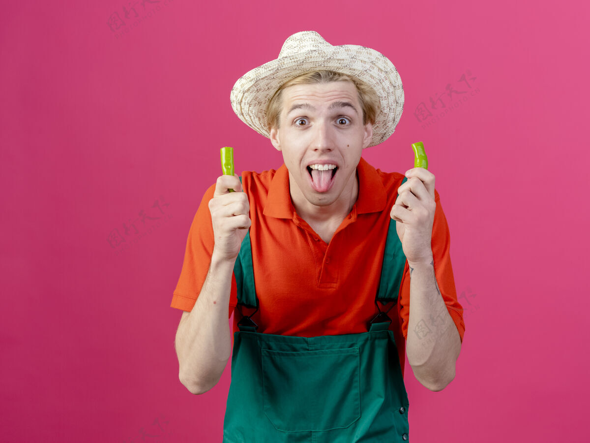 一半年轻的园丁 穿着连体衣 戴着帽子 手里拿着一半的青椒举行男人舌头