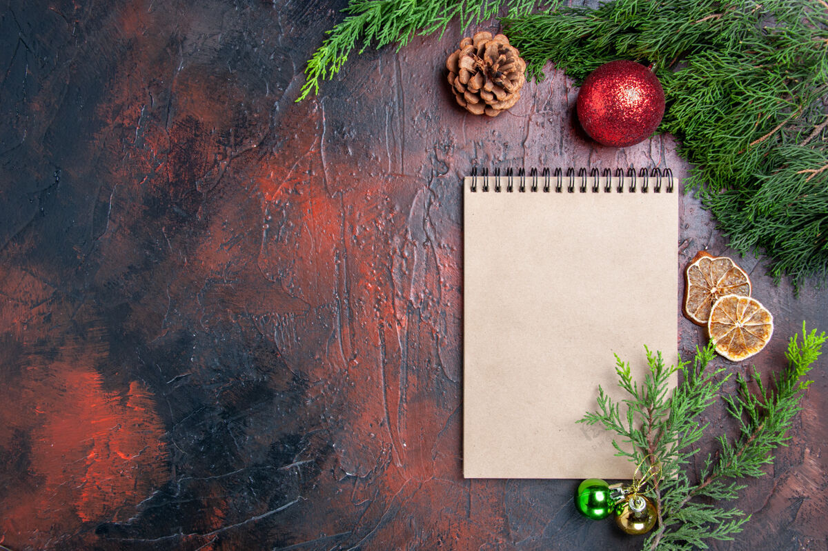 背景顶视图红笔笔记本松树枝圣诞树球玩具干柠檬片一杯茶暗红色表面免费空间圣诞照片茶切片笔