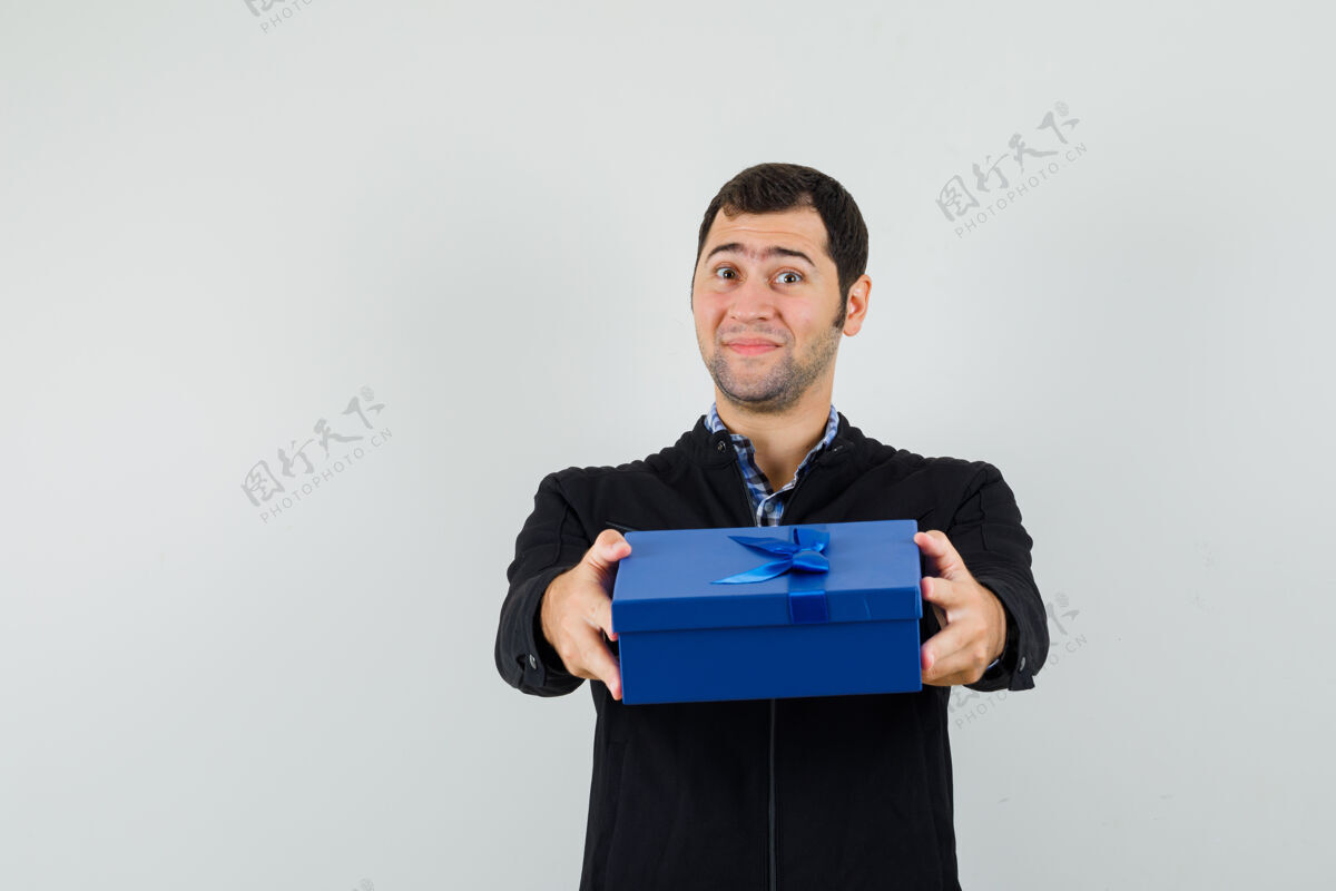 发型年轻人赠送礼品盒在衬衫 夹克衫和看起来温柔 前视图肖像微笑男人