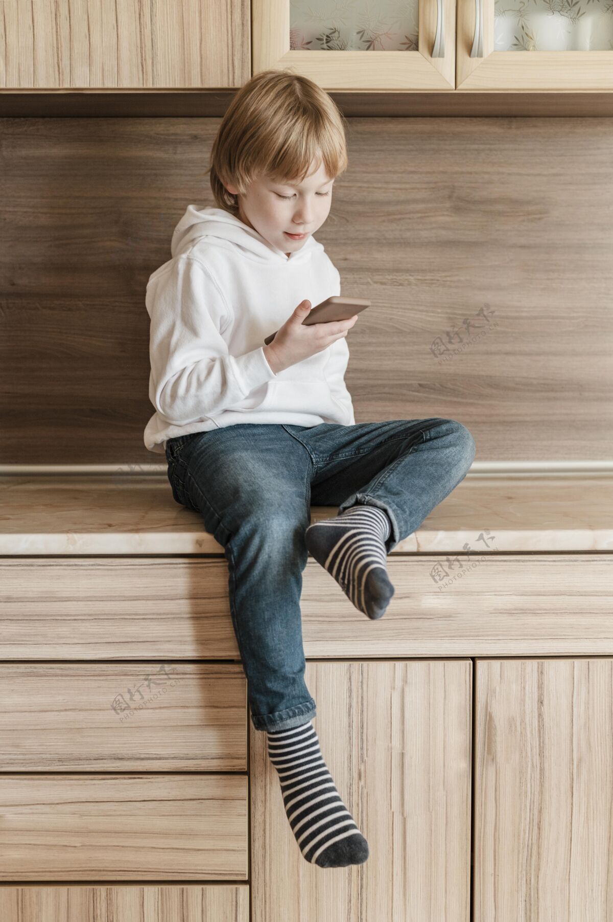 业余爱好小男孩使用智能手机的前视图垂直青年移动