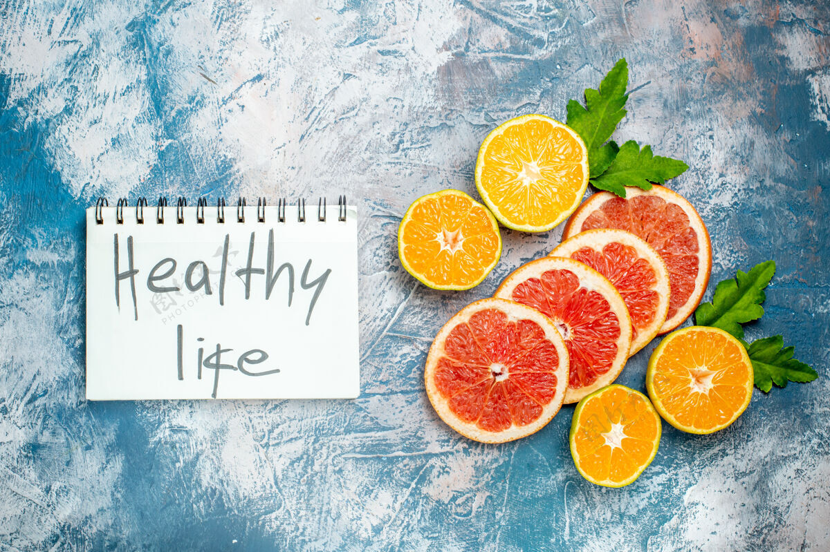 柑橘俯瞰写在笔记本上的健康生活切橘子和葡萄柚在蓝白色的表面橙子多汁顶部