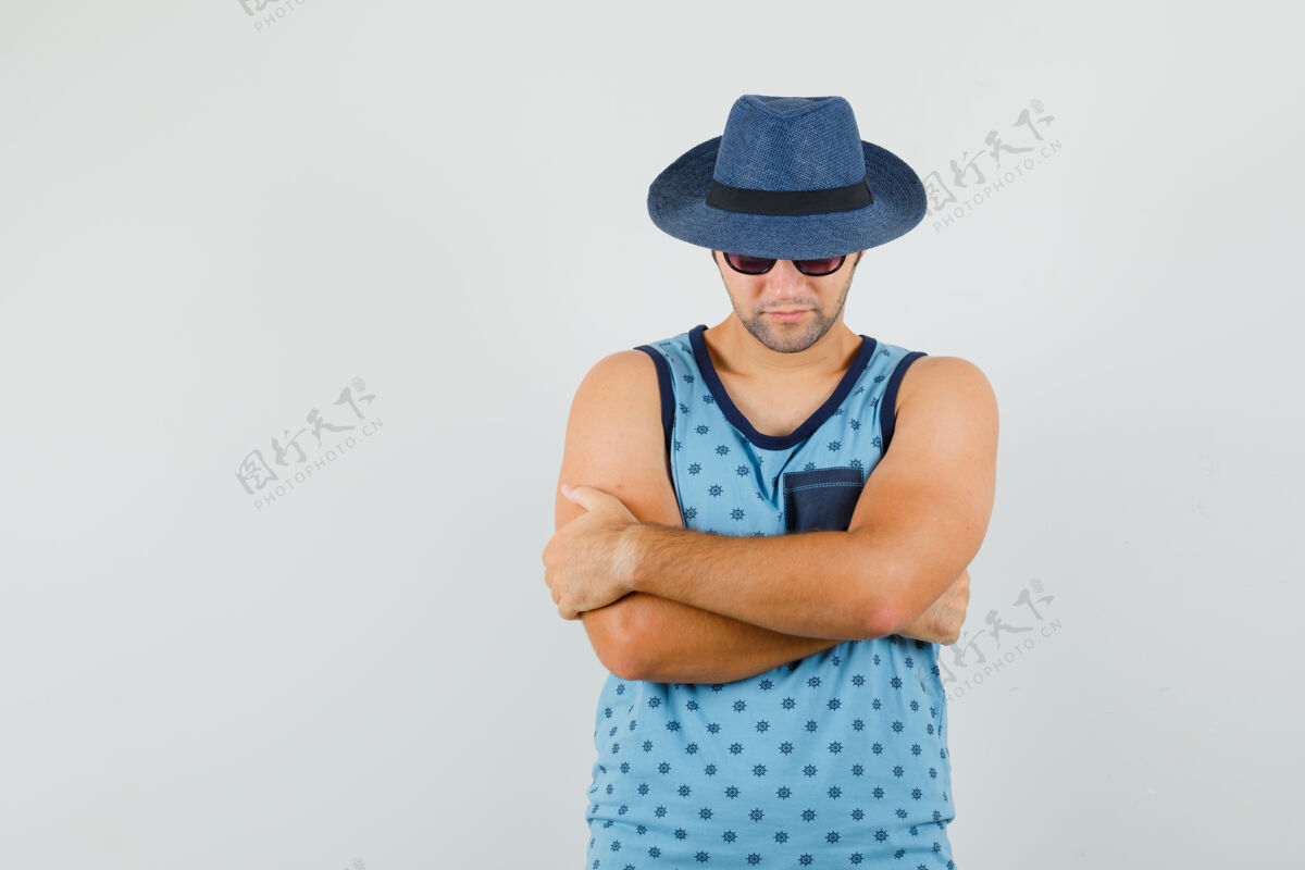 模特年轻人交叉着双臂站在蓝色的单人床上 戴着帽子 看上去很自信 正对着前方胡须男性肖像
