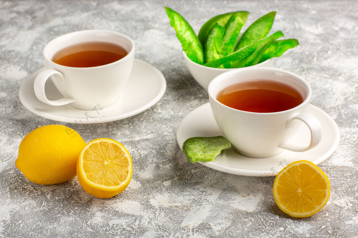 餐前视图：一杯浅白色表面上有柠檬的茶茶碟热的柑橘