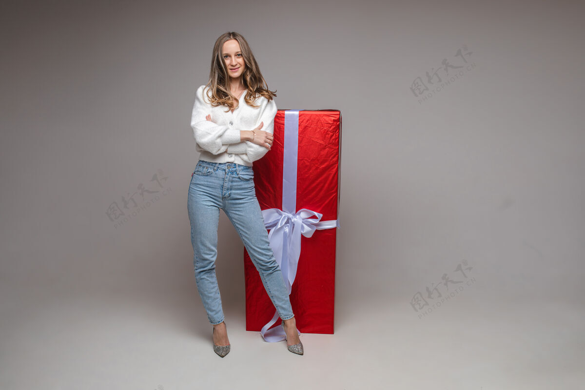 漂亮漂亮健康的年轻女子 在灰色工作室背景上有一个大红色礼物 并留有用于假日广告的复制空间女士问候完美