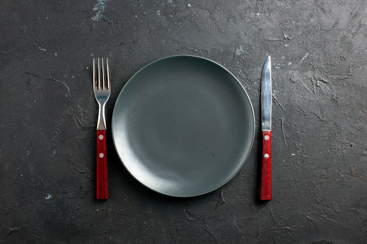 叉子俯视图黑色沙拉盘叉和刀在黑色表面厨房用具炒锅薯条