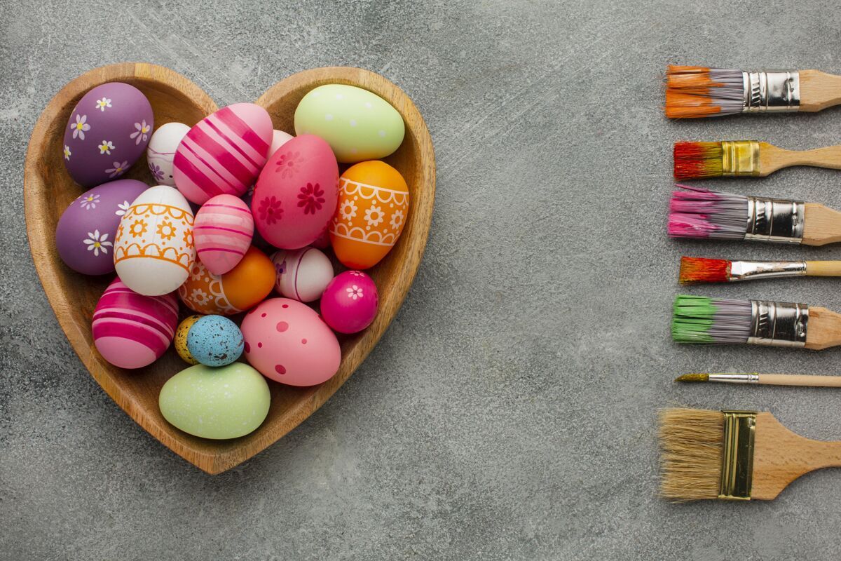 复活节彩色复活节彩蛋的顶视图在心形板与各种油漆刷鸡蛋盘子节日