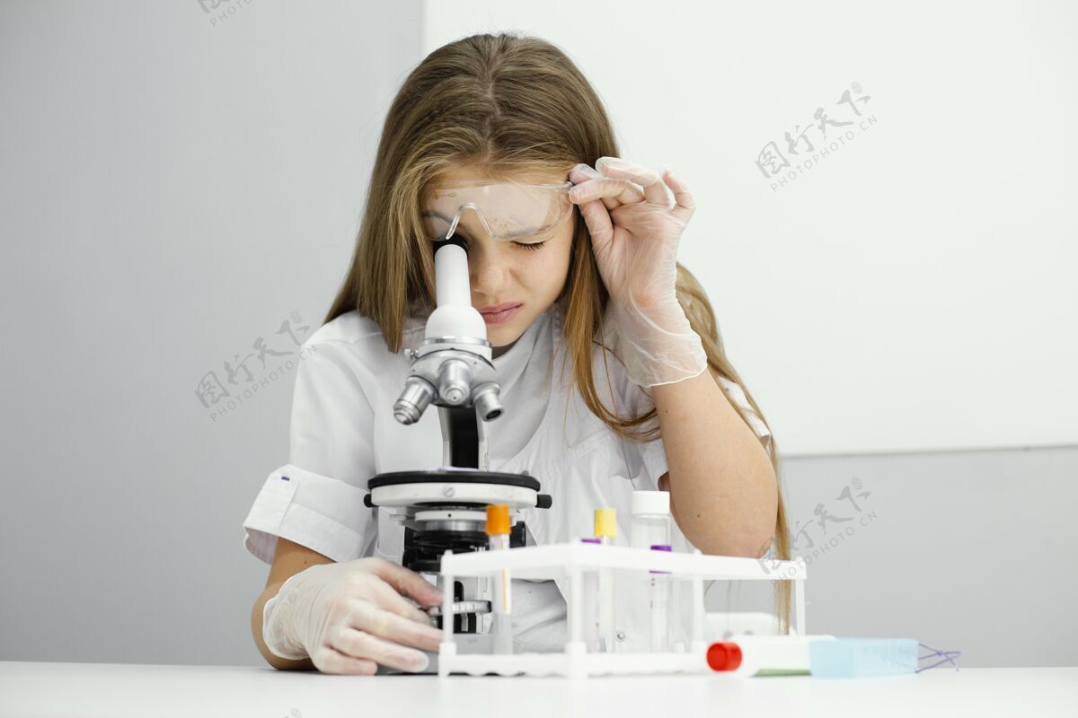 女孩好奇的年轻女科学家使用显微镜的前视图青年学习实验室