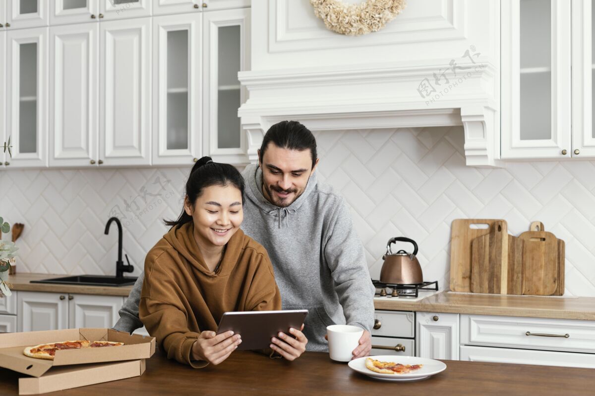 生活方式一对夫妇在厨房吃早餐 并使用平板电脑房子活动年轻