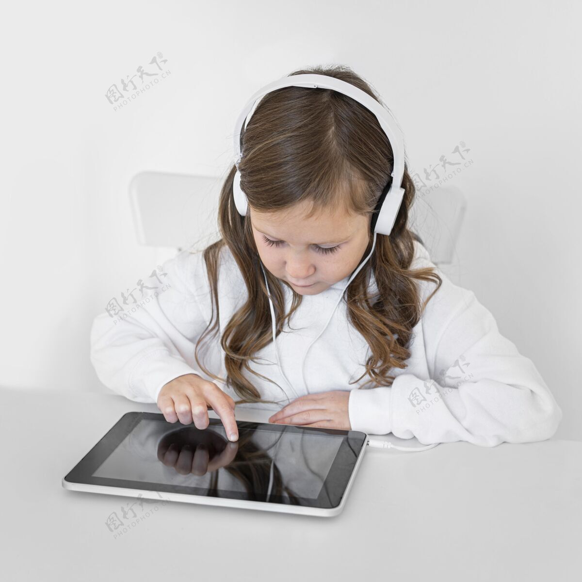 年轻人小女孩用带耳机的平板电脑消遣年轻人娱乐