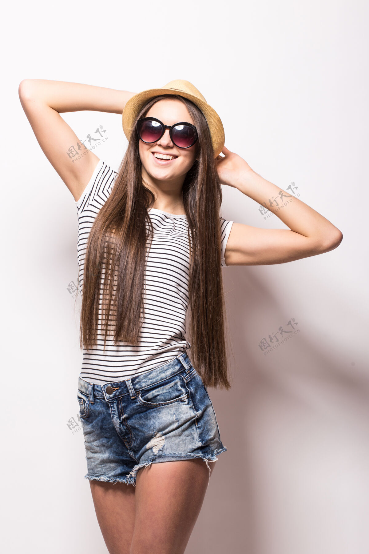 游客摄影棚里 一位面带笑容的开朗女人 戴着时髦的太阳镜 戴着草帽 穿着夏装 隔着白色的墙壁成人旅游快乐